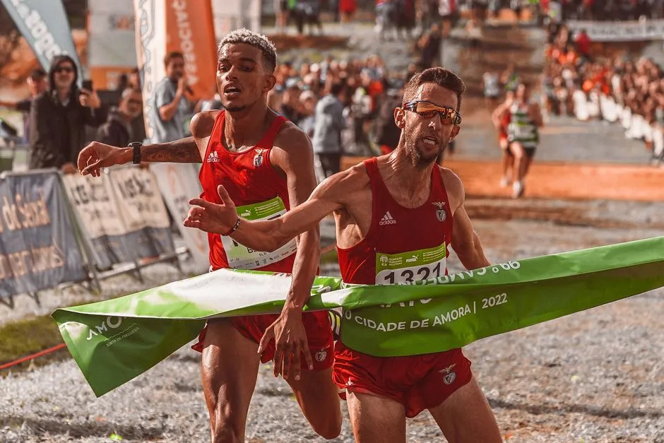 Coureur débutant avec dossard sur une ligne de départ, foule et banderole d’une course locale